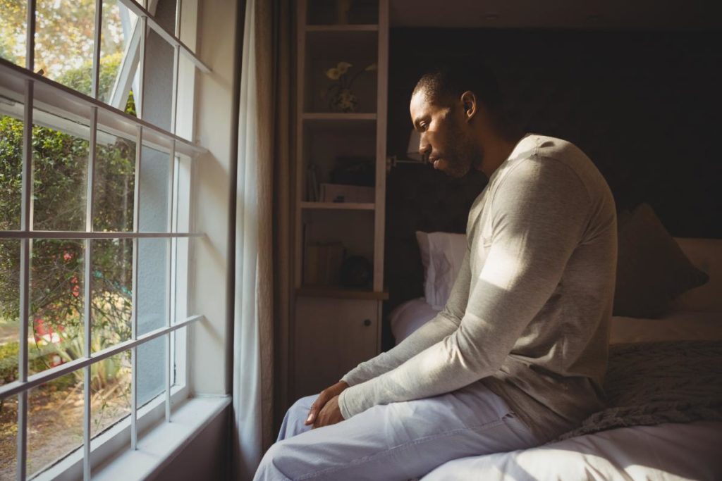 man sitting on his bed looking out the window thinking about the most commonly used benzodiazepines