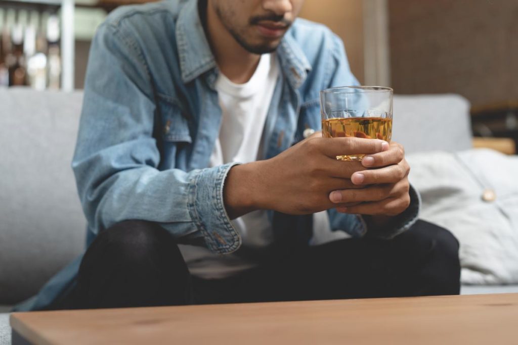 man holding an alcoholic drink in his hands and drinking to deal with anxiety