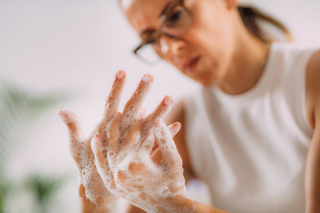 a woman is scrubbing her hands clean and thinking about the the connection between ocd and addiction