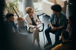 therapist talks to a group in group therapy about the importance of treating addiction and trauma together