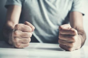 a photo of a persons hands in fists on a table and trying to understand how to cope with your anger