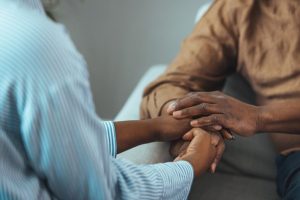 a person holds another persons hands while explaining the risks of a family history of addiction