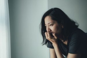 a woman sits worried thinking about depression symptoms