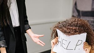 Person overwhelmed holding a help sign. Dual diagnosis treatment can be the help you need.