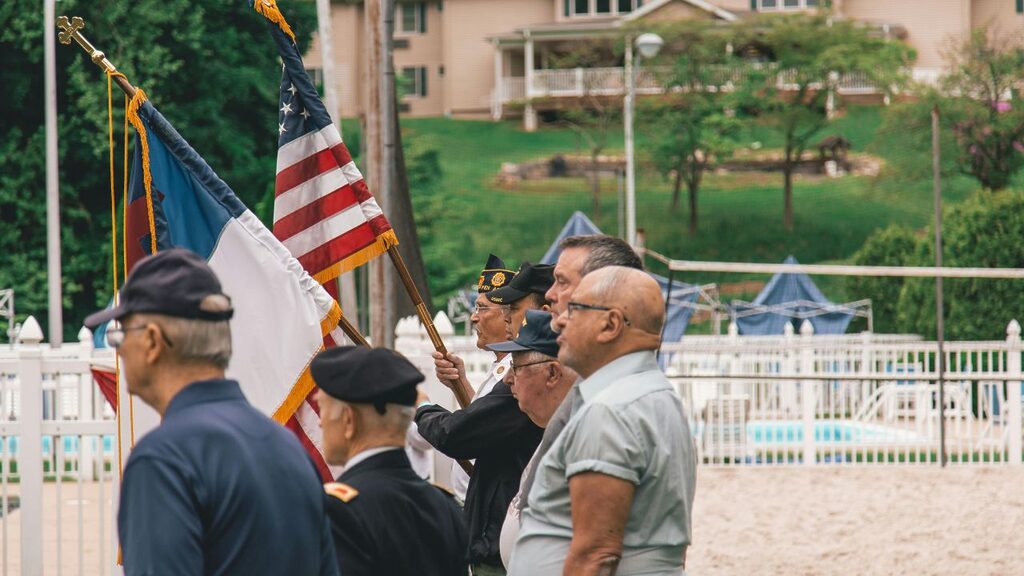 Shot of veterans holding up a flag. Learn about veteran's addiction treatment in this blog post.